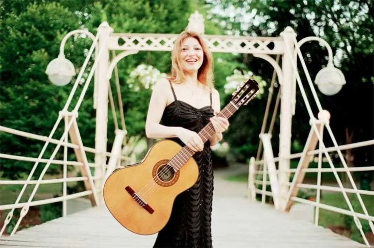 Irene Gómez holding acoustic guitar on bridge